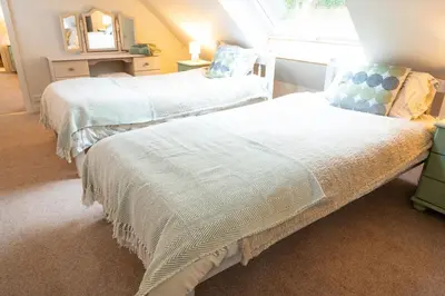 a bedroom with two beds with white sheets and a window at Gardeners Cottage in Auchencairn