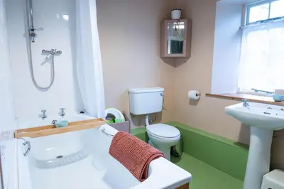 a bathroom with a tub and a toilet and a sink at Gardeners Cottage in Auchencairn