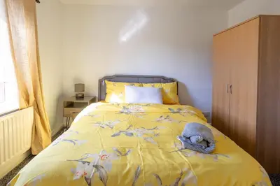 a bedroom with a bed with a yellow comforter at Charming 2br Maisonette In Carlisle Center in Carlisle