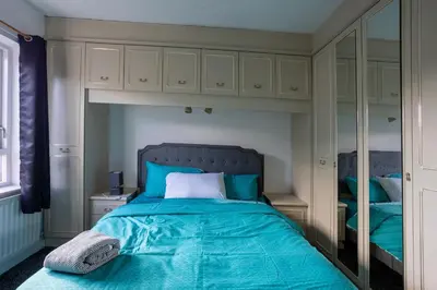 a bedroom with a bed with blue sheets and a mirror at Charming 2br Maisonette In Carlisle Center in Carlisle