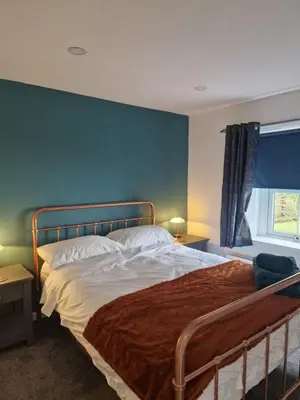 a bedroom with a bed and a blue wall at Victoria Cottage in Whitrigg