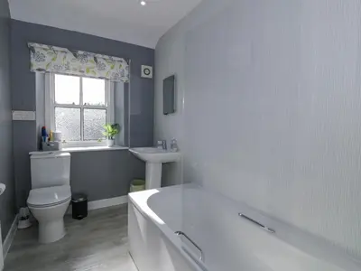 a bathroom with a tub and a toilet and a sink at Morton Mains Steading Cottage in Thornhill