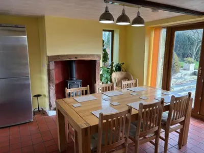 a dining room with a wooden table and a fireplace at Kingate Cottage in Aspatria