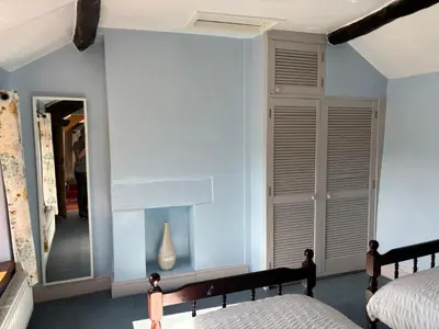 a bedroom with blue walls and a mirror at Kingate Cottage in Aspatria