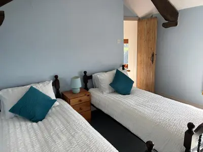 two beds in a room with blue pillows at Kingate Cottage in Aspatria