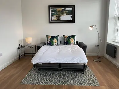 a bedroom with a white bed with a rug at 8 Clifton Terrace in Douglas