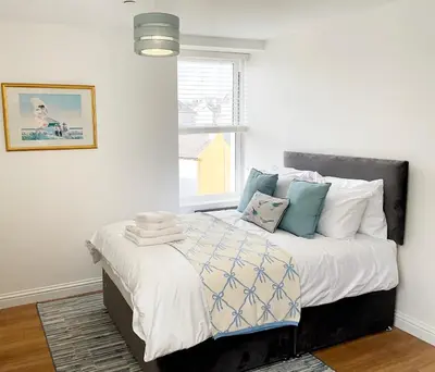 a bedroom with a bed with white and blue pillows at 8 Clifton Terrace in Douglas