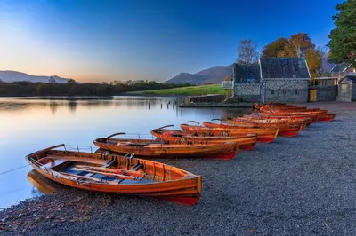 a row of wooden boats sitting on the water at 1 Bed in Uldale oc-m31080 in Uldale