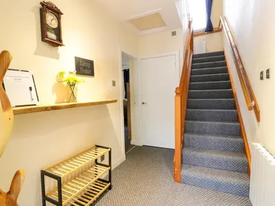 a hallway with stairs and a clock on the wall at The Lamphouse in Stranraer