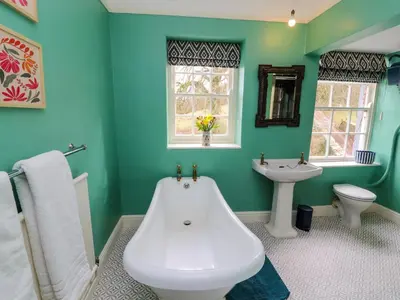 a green bathroom with a tub and a sink at Westward Park in Wigton