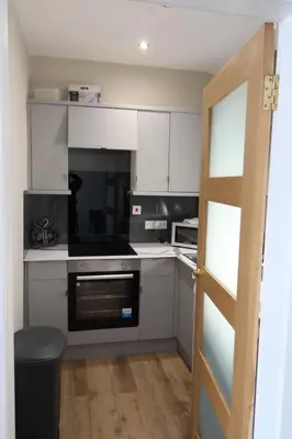 a kitchen with white cabinets and a stove top oven at Links Cottage, Prestwick in Prestwick