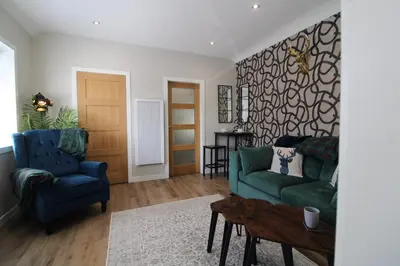 a living room with two blue chairs and a table at Links Cottage, Prestwick in Prestwick
