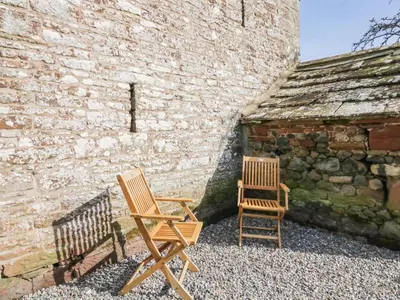 two wooden chairs sitting next to a brick wall at The Roost in Carlisle
