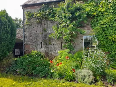 an old brick building with a garden of flowers at The Roost in Carlisle