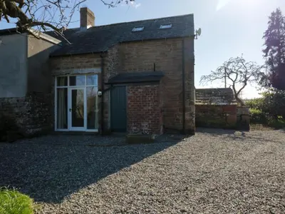 a brick house with a door and a gravel driveway at The Roost in Carlisle