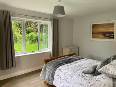 a bedroom with a bed and two windows at Orchard Cottage At Gretna in Gretna