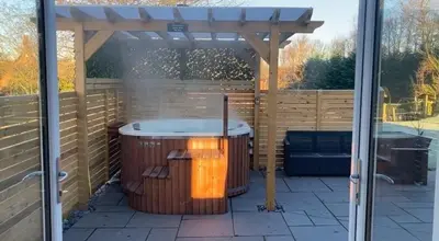 a hot tub sitting under a wooden pergola at Orchard Cottage At Gretna in Gretna