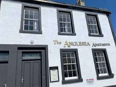 a white building with a sign that reads the americas antiquaries at The Harbour House Sea Front Hotel in Portpatrick