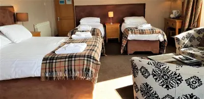 a hotel room with two beds and a couch at The Harbour House Sea Front Hotel in Portpatrick