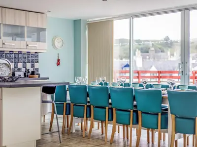 a dining room with a table and blue chairs at Holiday Home The Knowe by Interhome in Portpatrick