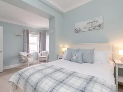 a bedroom with a large white bed with blue pillows at Holiday Home The Knowe by Interhome in Portpatrick