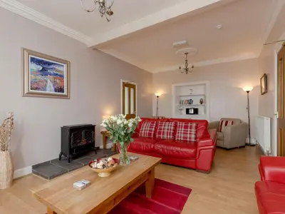 a living room with a red couch and a fireplace at Holiday Home The Knowe by Interhome in Portpatrick