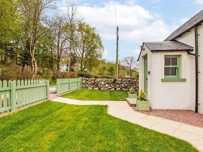 a backyard with a fence and a yard with green grass at Holiday Home Balbeg Cottage by Interhome in Straiton