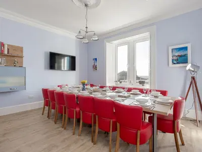 a dining room with a table and red chairs at Holiday Home Portpatrick House by Interhome in Portpatrick