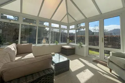 a living room with a couch and a table and windows at Fern Cottage in Portinscale