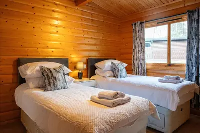 a bedroom with two beds in a log cabin at Ravens Craig in Kippford