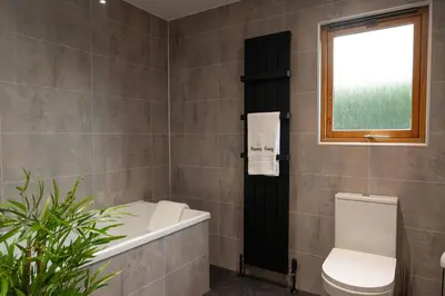 a bathroom with a tub and a toilet and a window at Ravens Craig in Kippford