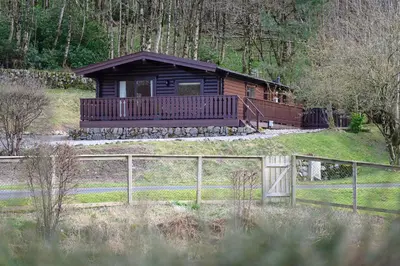 a log cabin with a fence in front of it at Ravens Craig in Kippford