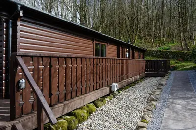 a wooden cabin with a fence next to a path at Ravens Craig in Kippford