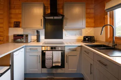 a kitchen with white cabinets and a stove top oven at Ravens Craig in Kippford