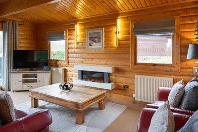 a living room with a fireplace and a coffee table at Ravens Craig in Kippford