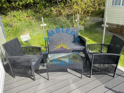 a patio with three chairs and a table with at Amblers Hide, Brigham, Cockermouth, Cumbria in Cockermouth