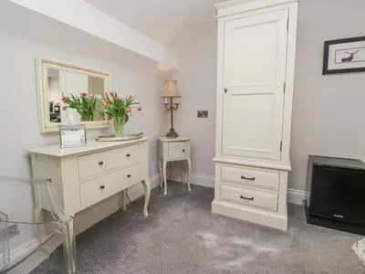 a white bedroom with a dresser and a mirror at Raise View House in Ambleside