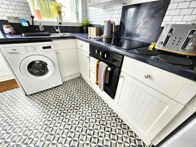 a kitchen with a washer and dryer on a floor at Leaf Tree Cottage, close to Coast, Lakes and Fells in Workington