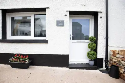 a white house with a white door and two windows at Leaf Tree Cottage, close to Coast, Lakes and Fells in Workington