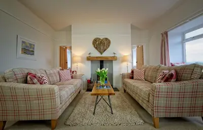 a living room with two couches and a table at Threaby Cottage in Girthon
