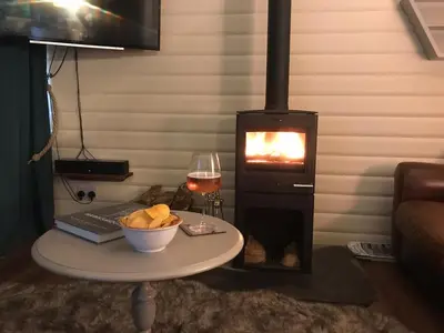 a table with a glass of wine and a stove at Rustic Secluded Hidden Gem At Rockhall in Dumfries