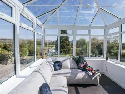 a glass house with a couch in a room with windows at Eildon Lodge in Seascale