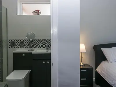 a bathroom with a sink and a toilet and a bed at Eildon Lodge in Seascale