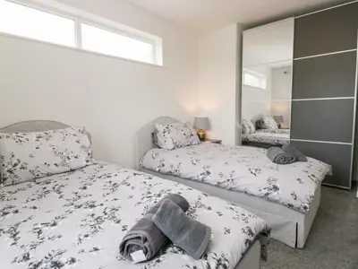 a bedroom with two beds and a mirror at Eildon Lodge in Seascale