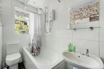 a white bathroom with a toilet and a sink at Heron View Cottage in Grasmere