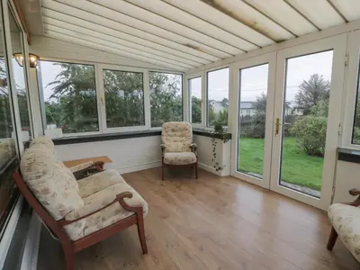 a room with windows and a couch and a chair at Swallow Cottage in Dumfries