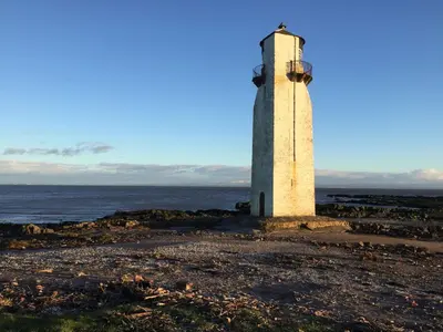 a lighthouse on the shore of the ocean at Swallow Cottage in Dumfries
