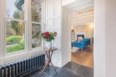 a hallway with a vase of flowers on a table next to a window at Huntingstile South in Ambleside