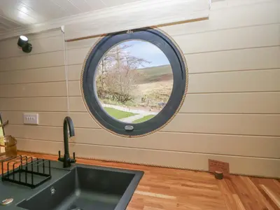 a round window in a kitchen with a sink at Longlands Lodge in Wigton