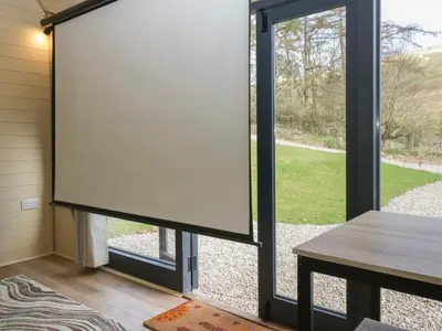 a screened in porch with a table and a large window at Binsey Lodge in Wigton